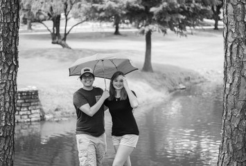 Attractive young couple outdoors with umbrella in monochrome