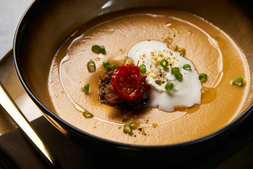 Hot Lentil cream soup with baked lamb, cream fresh and spearmint. Delicious healthy soup food in bowl plate on table background, close-up, top view