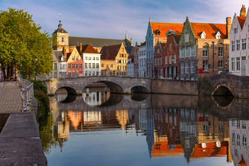Obraz premium Scenic city view of Bruges canal with beautiful medieval colored houses, bridge and reflections in the evening gold hour, Belgium
