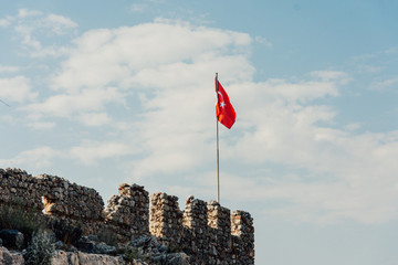 Alanya Kalesi. Flag in the fortress. Brick ancient castle walls. Turkish flag against the sky. Alanya, Turkey. Wonderful country. Ruins of the fortress of Alanya