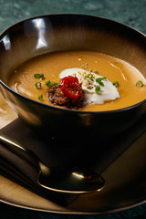 Hot Lentil cream soup with baked lamb, cream fresh and spearmint. Delicious healthy soup food in bowl plate on table background, close-up, top view