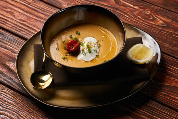 Traditional Lentil cream soup with baked lamb, cream fresh and spearmint. Delicious healthy soup food in bowl plate on table background, close-up, top view, copy space