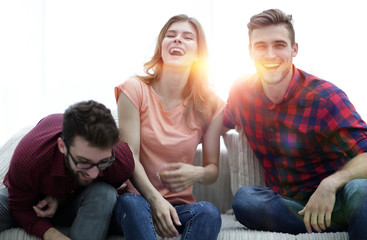 group of young people laughing and sitting on the couch