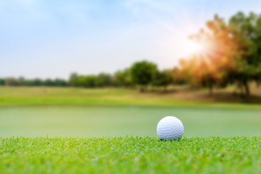 Golf ball on blurred beautiful green grass with sunlight in morning time. Sport and recreation playground for golf club concept.