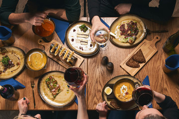 Table with food top view. People eat healthy meals at festive table served for party. Friends celebrate with organic food on wooden table view from above. Happy company having lunch, taking salad dish