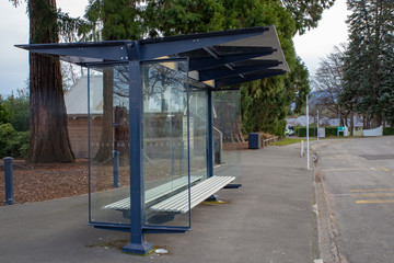 A glass and steel bus shelter beside a road