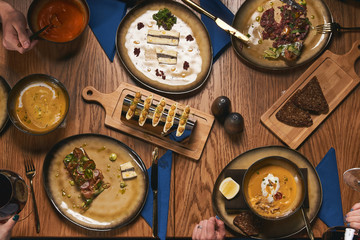 Table with food top view. People eat healthy meals at festive table served for party. Friends celebrate with organic food on wooden table view from above. Happy company having lunch, taking salad dish