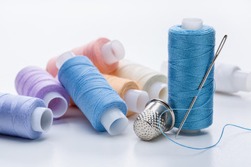  Set of multicolored threads on reels, large needle for sewing and  thimble.