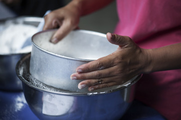 Cook is sifting flour to make bakery