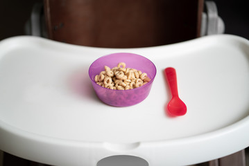 Kid Cereal In Fun Colorful Bowl On A High Chair