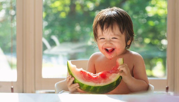 Happy Toddler Boy Eating Watermelon In His Highchair