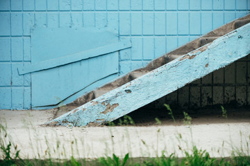 Blue wall of building with hatch and stairway close up. Steps against wall of blue tiles. Background with porch with copy space.
