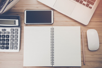 Mix of office supplies and gadgets on a wooden desk .