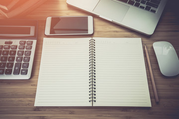 Mix of office supplies and gadgets on a wooden desk .