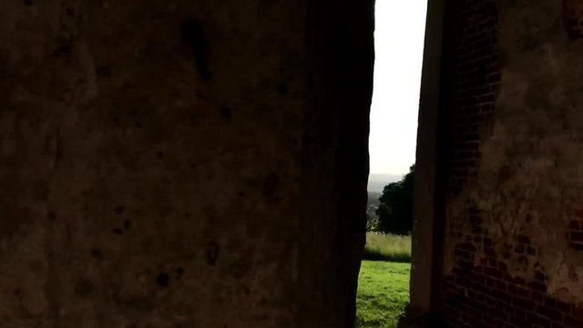 A sweeping shot from the inside of an old hallway, looking out through an old set of pillars at the lovely scenery outside.