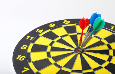 Closeup of three darts at the center of dartboard. A symbol of collective focusing on the target of business.
