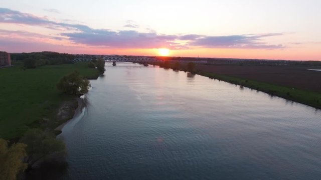 River Maas sunset drone shot with a train bridge in the background