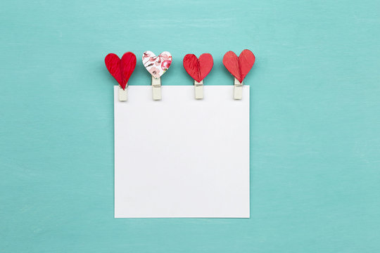 Red heart clip design with blank white paper on blue background 