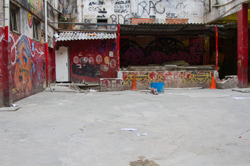 Stage in the courtyard of a ruined worn abandoned building with walls painted by colorful graffiti used as slum by poor people. No people.