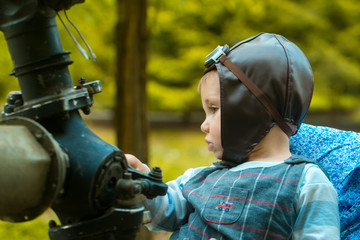 Child pilot in aviator helmet sitting at metal gear