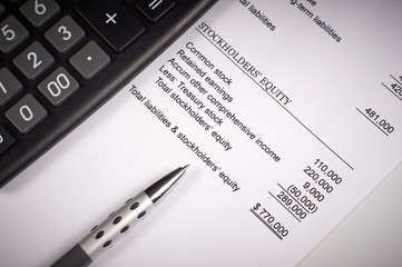 balance sheet on a white sheet of paper, calculator and pen