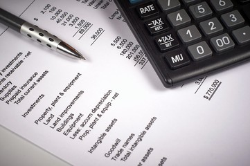 balance sheet on a white sheet of paper, calculator and pen
