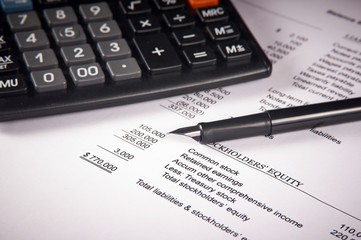 balance sheet on a white sheet of paper, calculator and pen
