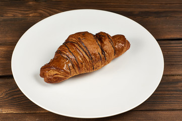 Chocolate croissant on white plate, closeup
