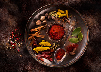 Indian spices and herbs on a plate on a dark concrete background - obrazy, fototapety, plakaty