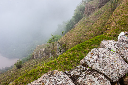 Farming terraces on a cliff with a river and mountains in mist on the background. No people.