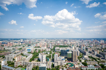 Helicopter drone shot. Aerial photography of a modern city over an area, a large crossroads, high-rise buildings, a park and roads. Panoramic city shot from above