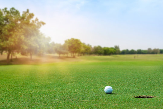 Golf ball on blurred beautiful green grass with sunlight in morning time. Sport and recreation playground for golf club concept.