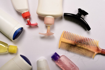Comb with hair and shampoo bottles on white background