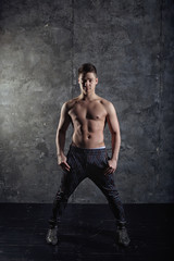 Portrait of strong healthy handsome Athletic Man Fitness Model posing near dark gray wall