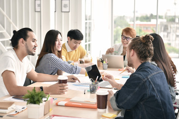 Group of young businesspersons having discussion and sharing opinions in meeting at office