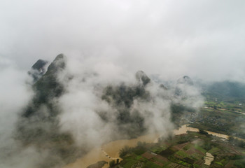 aerial view of cloudscape above farmland and mountain
