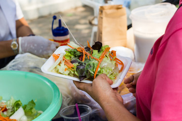 Hands give and get salad with blur people background, buy salad or fresh vegetable