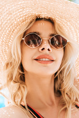 portrait of beautiful smiling young blonde woman in sunglasses and wicker hat