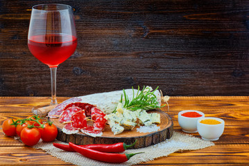 Sliced cured sausage with spices and a glass of red wine.