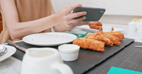 Woman taking photo on fried chicken wind in restaurant