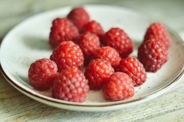 Ripe fresh sweet raspberries in a bowl on wooden table background