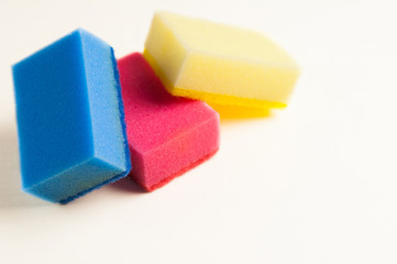 Heap of three red blue and yellow sponges for dishwashing on white background with copy space. Cleaning concept