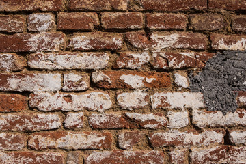 Beautiful wallpaper background of a worn red brick wall with white paint and concrete. No people.