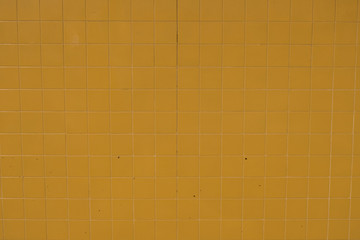 Wall surface made of yellow tiles. Wallpaper image of textures.