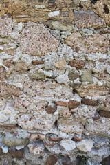 Vertical view of a medieval rough brick and stone wall texture.