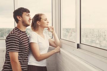 Happy girl and guy, cute couple looking out the window in their new home