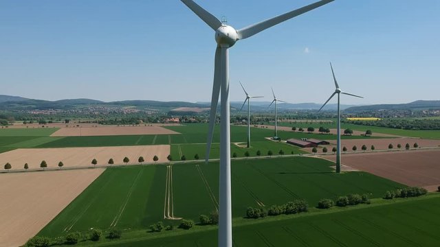Drone capture of wind wheels obove green fields.