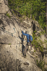 Obraz premium Climber in helmet and with special climbing equipment climbs on a rock