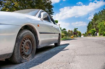 broken car in the background of the street and the blue sky. Broken side windows in the car. Street...