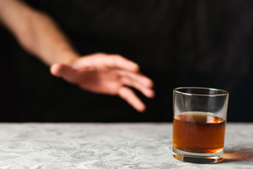 Man hand and transparent glass with alcohol on gray cement on black background